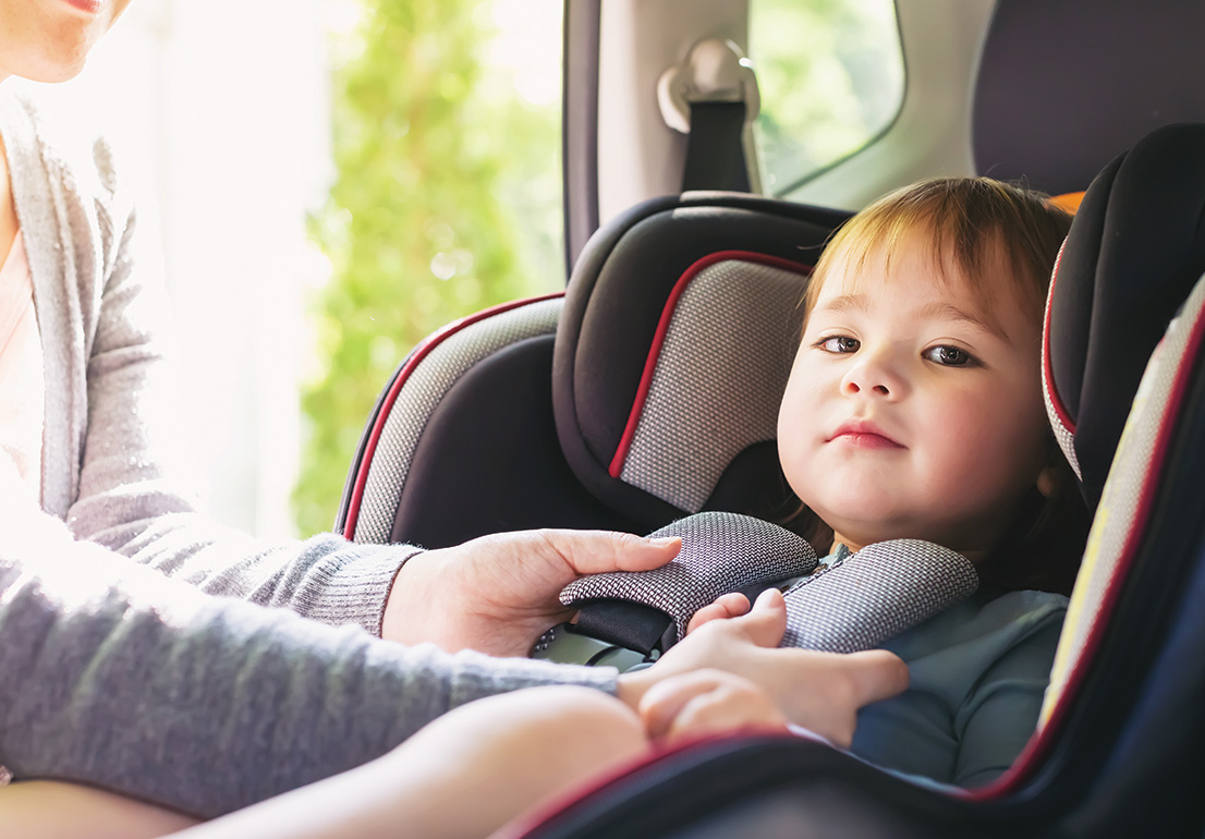 A parent buckles a child into a car seat